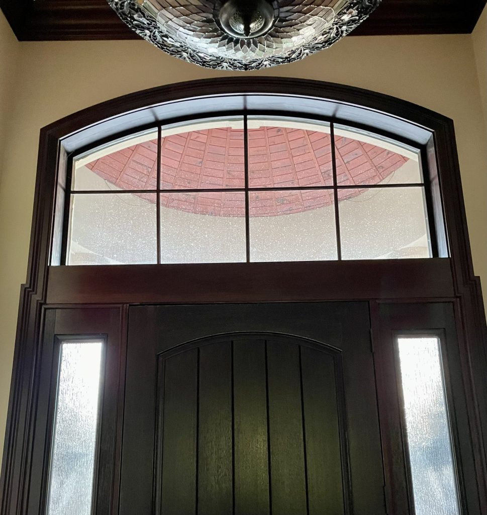 Entry door with decorative window film above and on the sides.