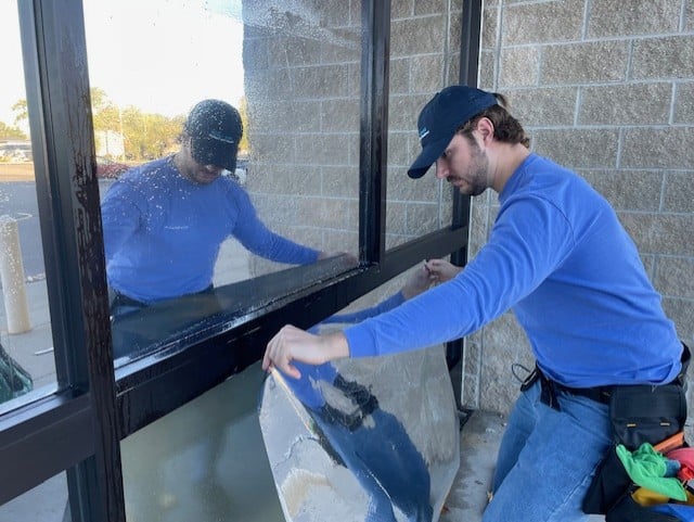 Man in blue shirt installing a window